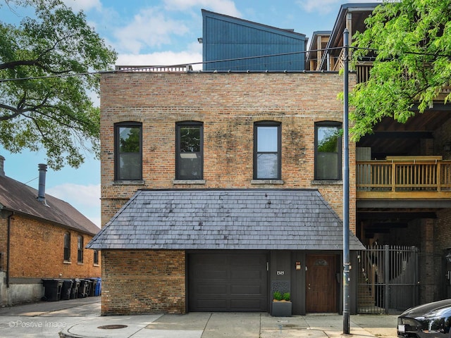 rear view of property with an attached garage, concrete driveway, and brick siding