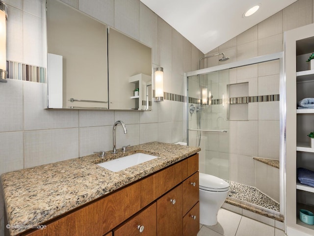 bathroom with tile walls, toilet, a shower stall, tile patterned flooring, and vaulted ceiling