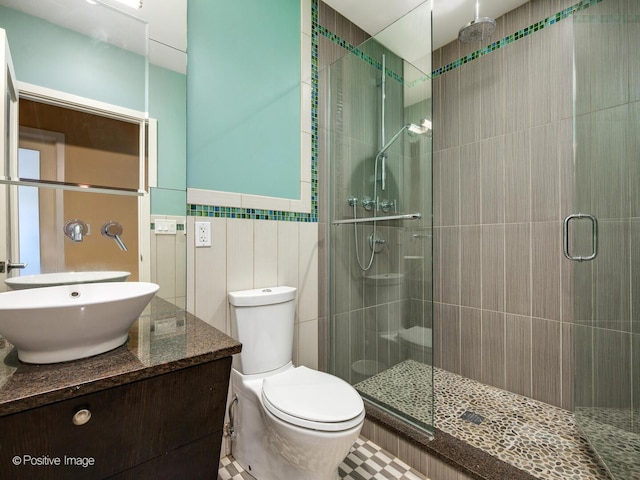 bathroom featuring tile walls, toilet, a shower stall, and vanity