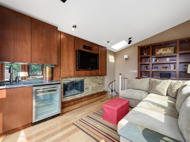 living room featuring beverage cooler, light wood-style flooring, and lofted ceiling with skylight