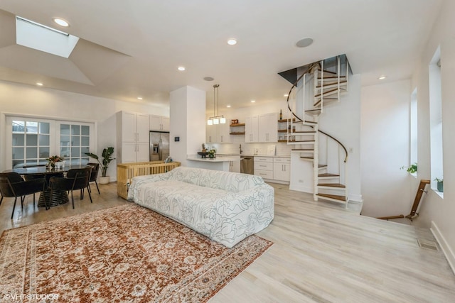 living area with recessed lighting, baseboards, light wood finished floors, visible vents, and stairway