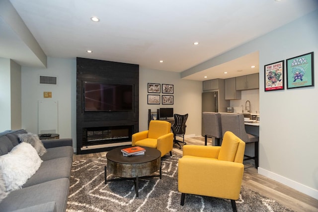 living room featuring light wood finished floors, baseboards, visible vents, and recessed lighting