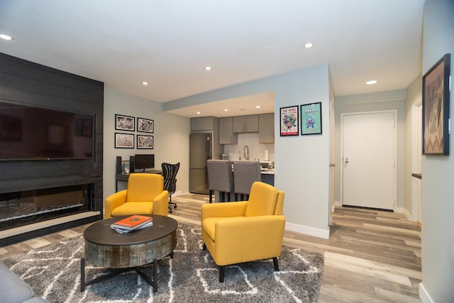 living area with baseboards, light wood finished floors, recessed lighting, and indoor wet bar