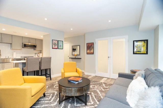 living area with light wood-style floors, french doors, baseboards, and recessed lighting
