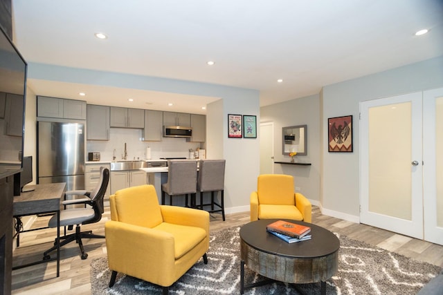 living area with baseboards, wet bar, recessed lighting, and light wood-type flooring