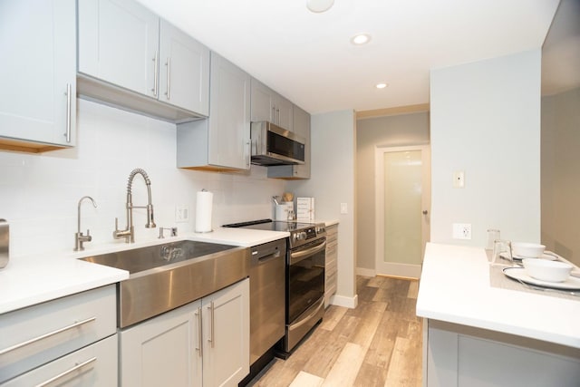 kitchen featuring light countertops, stainless steel appliances, a sink, and decorative backsplash