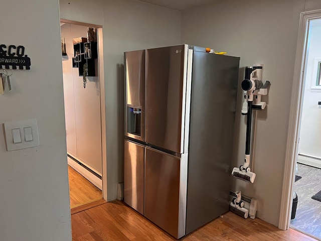 kitchen with wood finished floors, stainless steel refrigerator with ice dispenser, and a baseboard heating unit