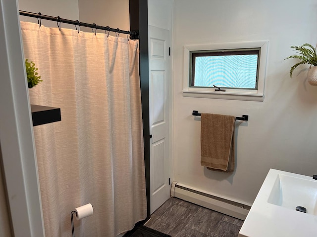full bath featuring curtained shower, baseboards, a baseboard heating unit, and a sink
