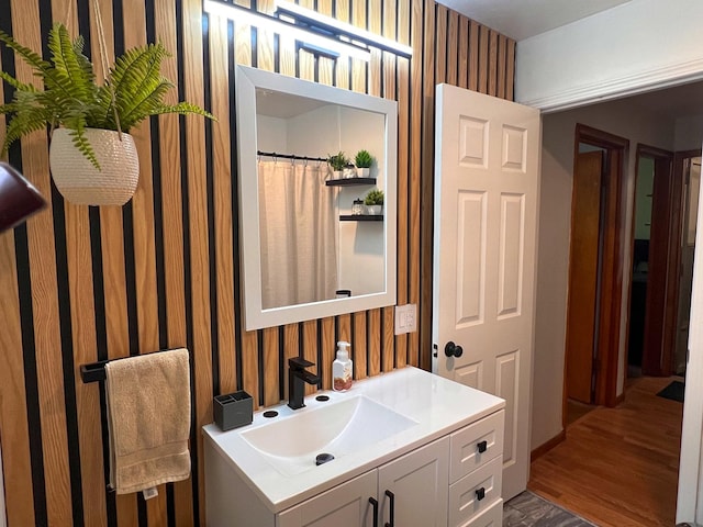 bathroom with wallpapered walls, wood finished floors, and vanity