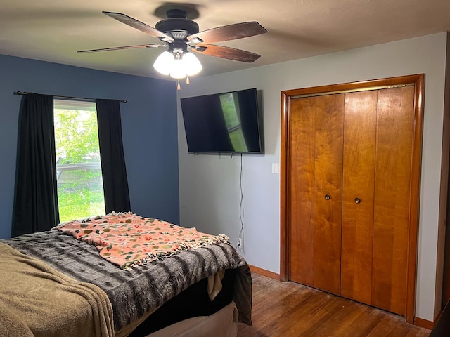 bedroom with a closet, baseboards, a ceiling fan, and wood-type flooring