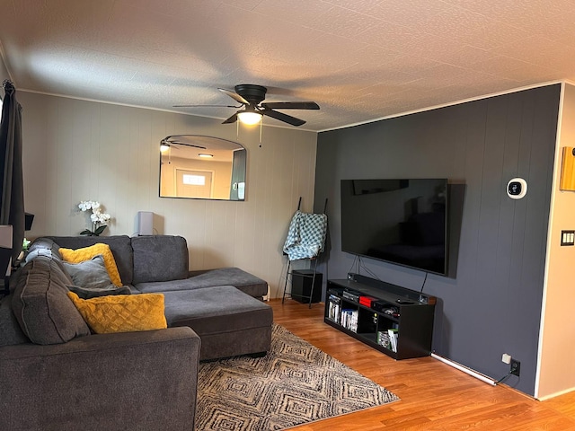 living room with wood finished floors, a ceiling fan, and ornamental molding
