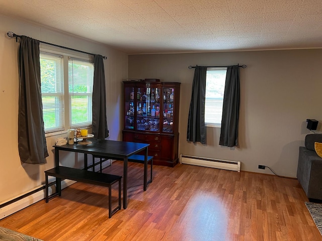 dining area with a baseboard radiator, light wood-style flooring, and plenty of natural light