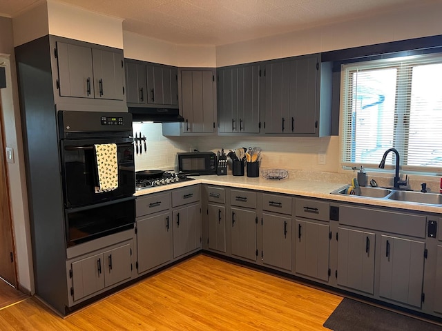 kitchen featuring a sink, gray cabinets, black appliances, a warming drawer, and tasteful backsplash