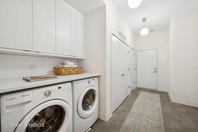 washroom featuring washing machine and clothes dryer, cabinet space, and baseboards