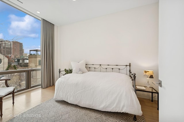 bedroom featuring wood finished floors, expansive windows, and recessed lighting