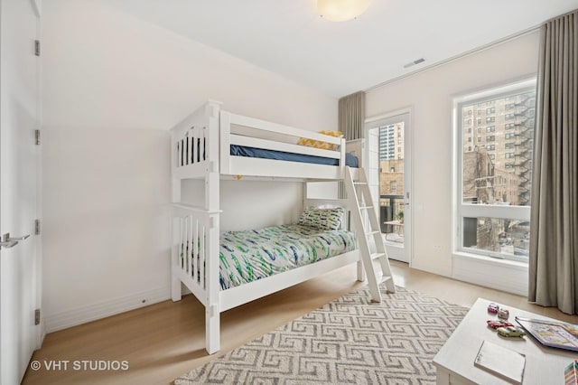 bedroom with wood finished floors, baseboards, and access to exterior