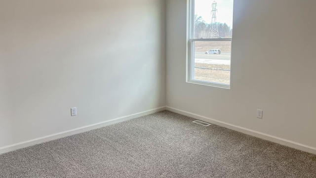 unfurnished room with carpet, baseboards, visible vents, and a wealth of natural light