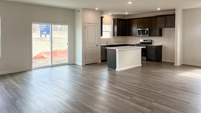 kitchen featuring a sink, dark wood-style flooring, appliances with stainless steel finishes, a kitchen island, and recessed lighting
