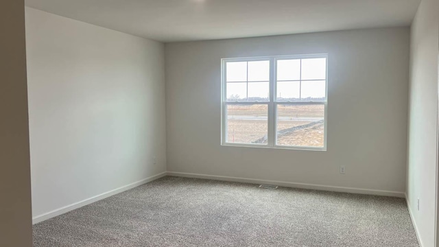 unfurnished room with baseboards, carpet flooring, and visible vents