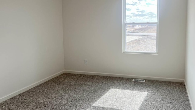 carpeted empty room featuring baseboards, a healthy amount of sunlight, and visible vents