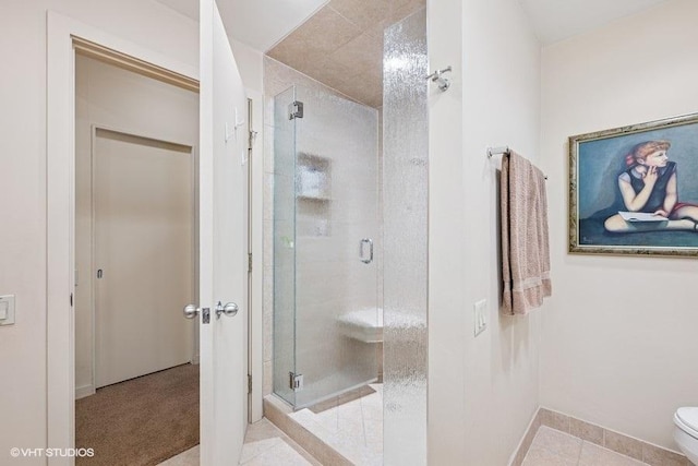 bathroom with toilet, baseboards, tile patterned flooring, and a shower stall