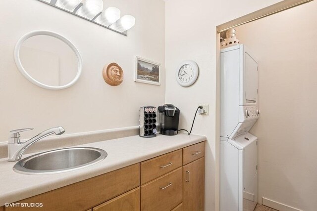 clothes washing area featuring a sink, laundry area, and stacked washer / dryer