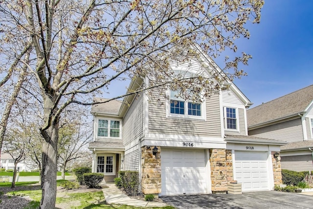 view of front facade featuring an attached garage, stone siding, and driveway