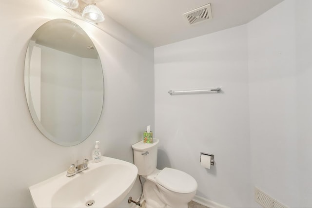 half bathroom with toilet, visible vents, and a sink