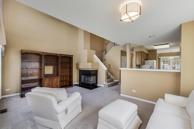 living area with stairs, visible vents, carpet flooring, baseboards, and a glass covered fireplace