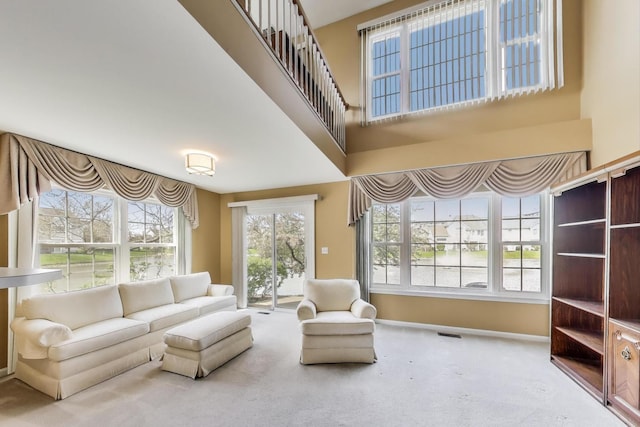 interior space with baseboards, carpet flooring, visible vents, and a towering ceiling