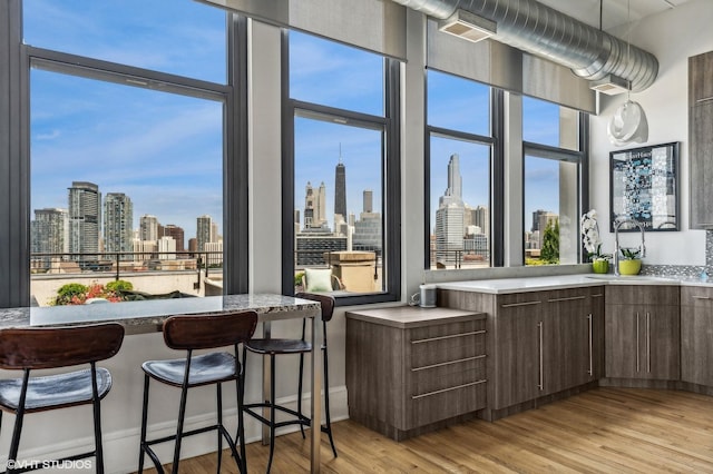 900 N Kingsbury St Unit 1150, Chicago, IL 60610 - kitchen featuring a skyline view, light wood-type flooring, modern cabinets, a kitchen breakfast bar, and dark brown cabinetry
