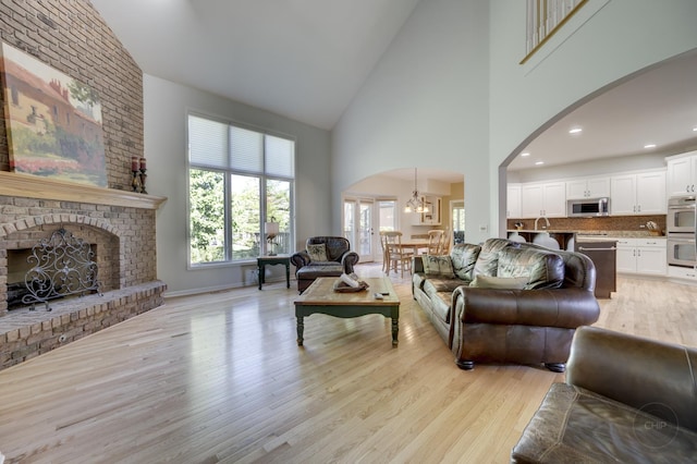 2411 Williamstown Ct, Naperville, IL 60564 - living area featuring high vaulted ceiling, arched walkways, light wood-style floors, a chandelier, and a fireplace