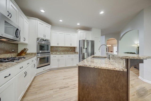 2411 Williamstown Ct, Naperville, IL 60564 - kitchen featuring stainless steel appliances, a sink, arched walkways, light wood-type flooring, and recessed lighting