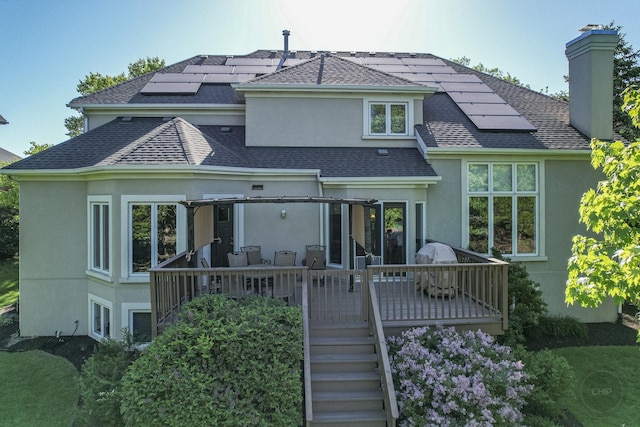 2411 Williamstown Ct, Naperville, IL 60564 - rear view of house with stucco siding, a chimney, solar panels, a shingled roof, and a wooden deck