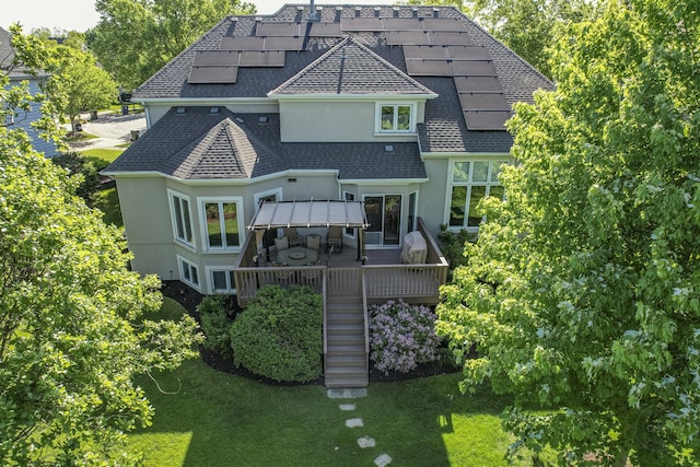 2411 Williamstown Ct, Naperville, IL 60564 - rear view of house featuring roof with shingles, stucco siding, roof mounted solar panels, stairs, and a yard