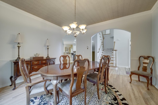 2411 Williamstown Ct, Naperville, IL 60564 - dining space featuring arched walkways, light wood finished floors, stairs, a chandelier, and crown molding