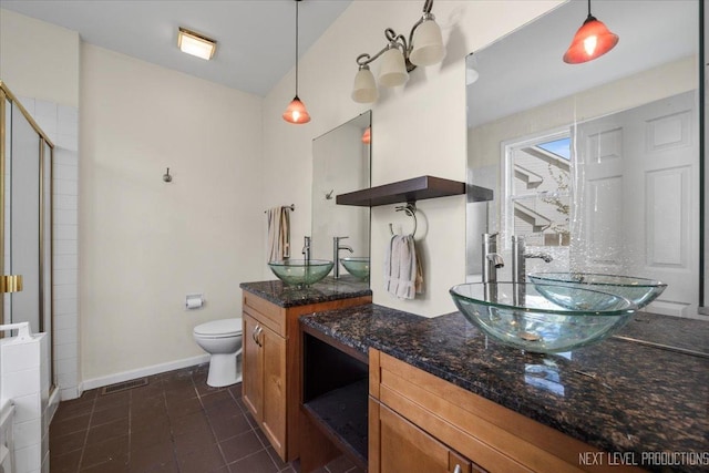 full bathroom with a shower stall, baseboards, toilet, two vanities, and tile patterned floors