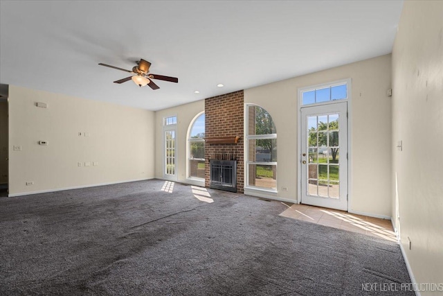 unfurnished living room with carpet, ceiling fan, a fireplace, and baseboards