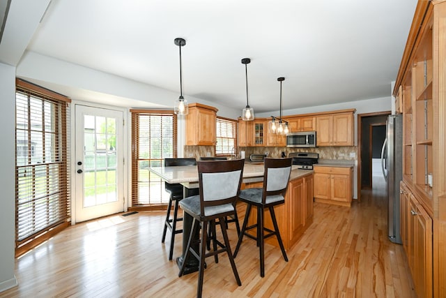 1408 Ambleside Cir, Naperville, IL 60540 - kitchen featuring appliances with stainless steel finishes, a breakfast bar, light wood finished floors, tasteful backsplash, and glass insert cabinets