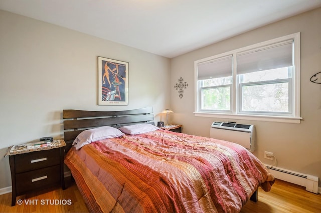 bedroom with wood finished floors, a baseboard heating unit, a wall mounted AC, and baseboards