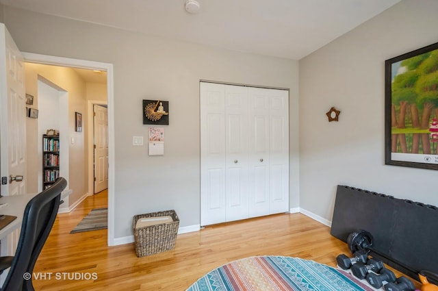 bedroom featuring light wood-style flooring, a closet, baseboards, and an office area