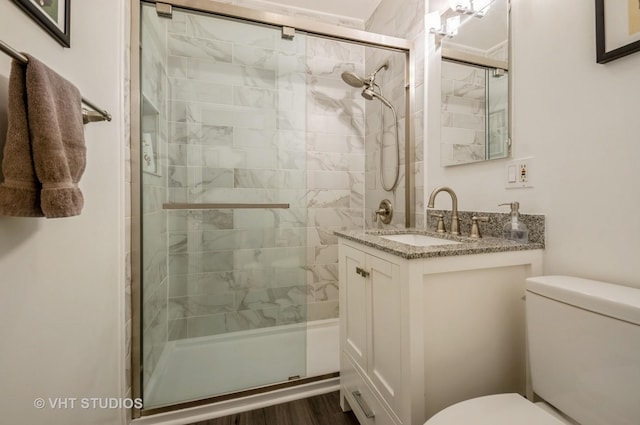 bathroom featuring toilet, a shower stall, and vanity