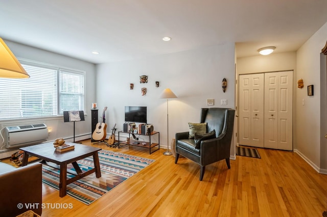living area featuring wood finished floors, a wall mounted AC, baseboards, and recessed lighting