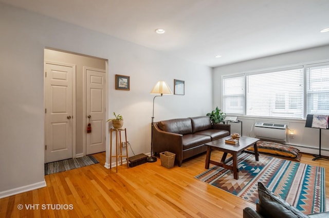 living room with light wood-style flooring, a wall mounted air conditioner, recessed lighting, and baseboards