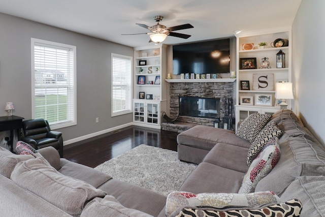 living area with a ceiling fan, baseboards, built in features, wood finished floors, and a fireplace