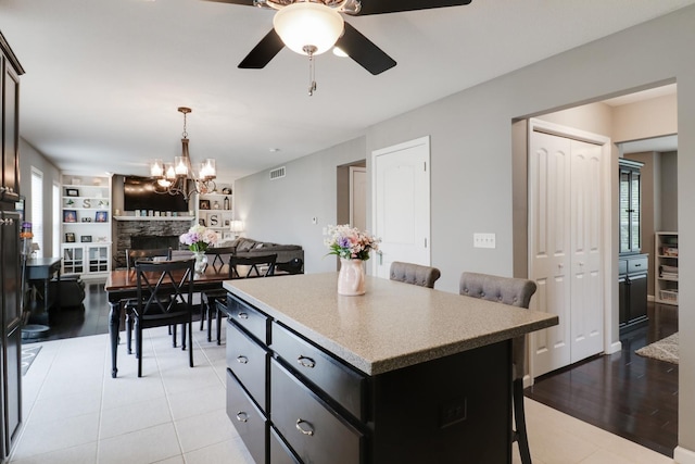 kitchen with a center island, a breakfast bar, visible vents, ceiling fan with notable chandelier, and open floor plan