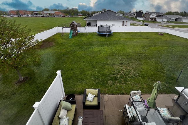 view of yard with a fenced backyard, a trampoline, and a playground