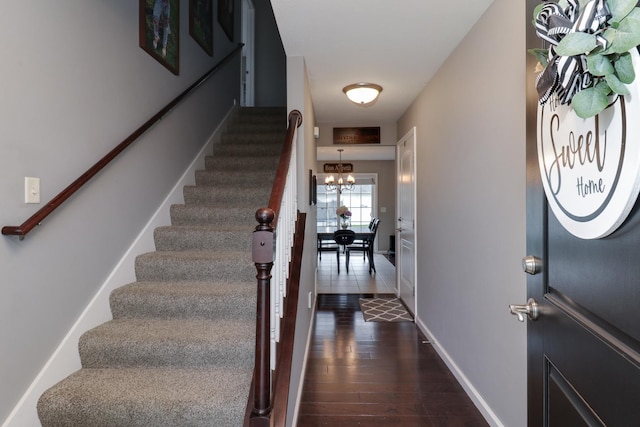 foyer entrance featuring baseboards, a notable chandelier, stairway, and dark wood-style floors