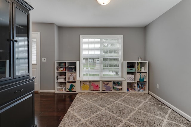 playroom featuring baseboards and dark wood finished floors