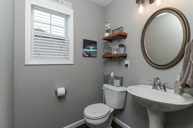 bathroom featuring baseboards, toilet, and a sink